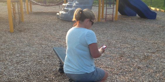 Frau verteidigt Mama, die auf Spielplatz am Handy hängt.